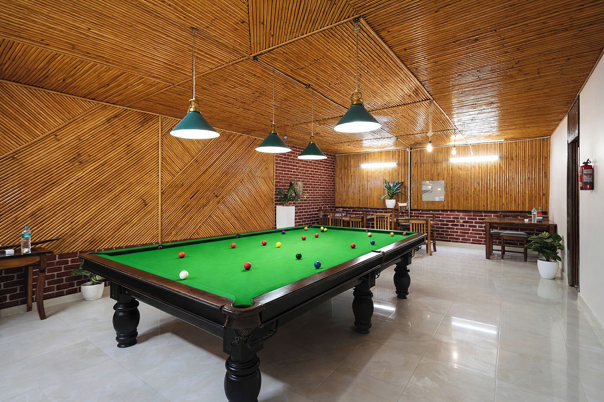 A pool table in a room with wooden walls and ceiling, green felt, and multiple hanging lights.