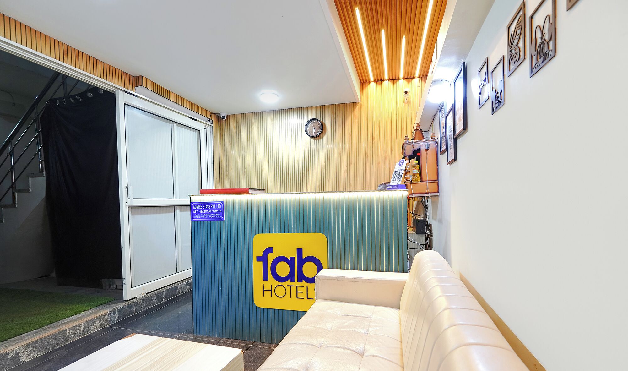 A hotel lobby with a reception desk, a clock, and framed artwork on the wall.