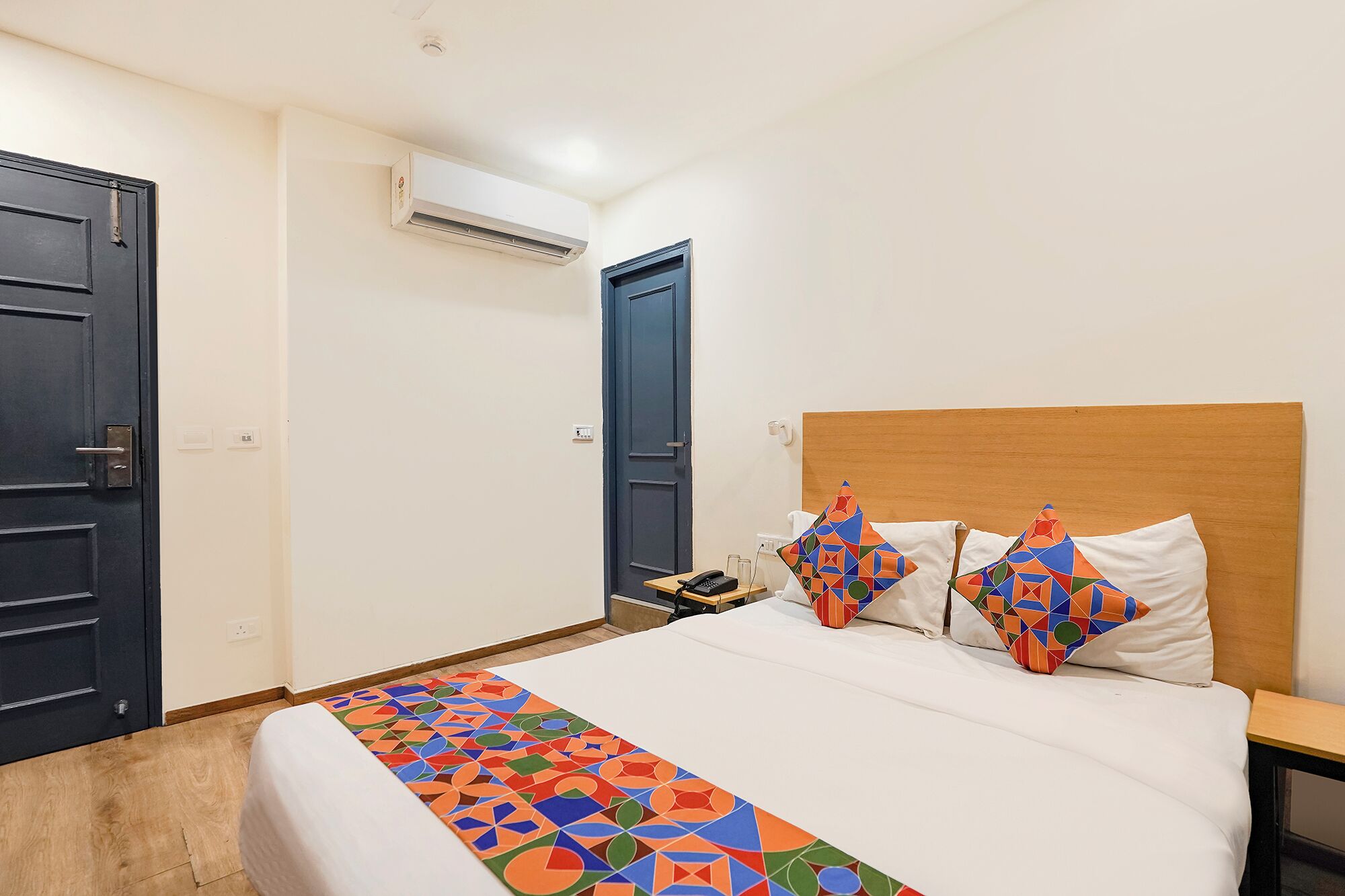 Une chambre d’hôtel équipée d’un lit, de deux oreillers, d’une table de chevet, d’un téléphone et d’un appareil de climatisation.