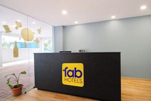 Una recepción con el logotipo de 'fab hotels' y una planta en maceta en el suelo.