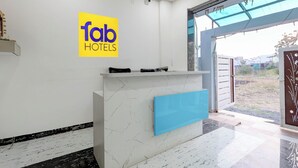 A reception desk with a 'fab hotels' sign, a glass door entrance, and a view of the outside. - Fabhotel Welcome Inn Besa (Nagpur)