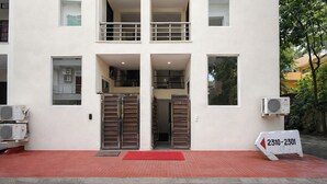 A building with a red carpet, double doors, and a sign with a phone number. - FabHotel Royal (Gurugram)