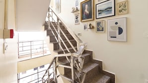 A staircase with metal railings leading to a landing with a view of the outside. - FabHotel Royal (Gurugram)