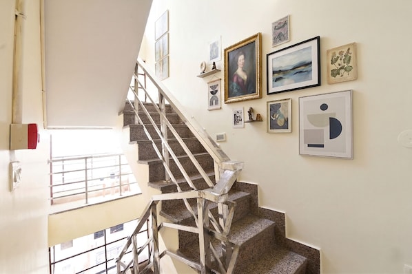 A staircase with metal railings leading to a landing with a view of the outside.