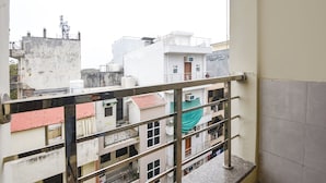 A balcony with a metal railing overlooking a residential area with buildings of various heights and architectural styles. - FabHotel Royal (Gurugram)