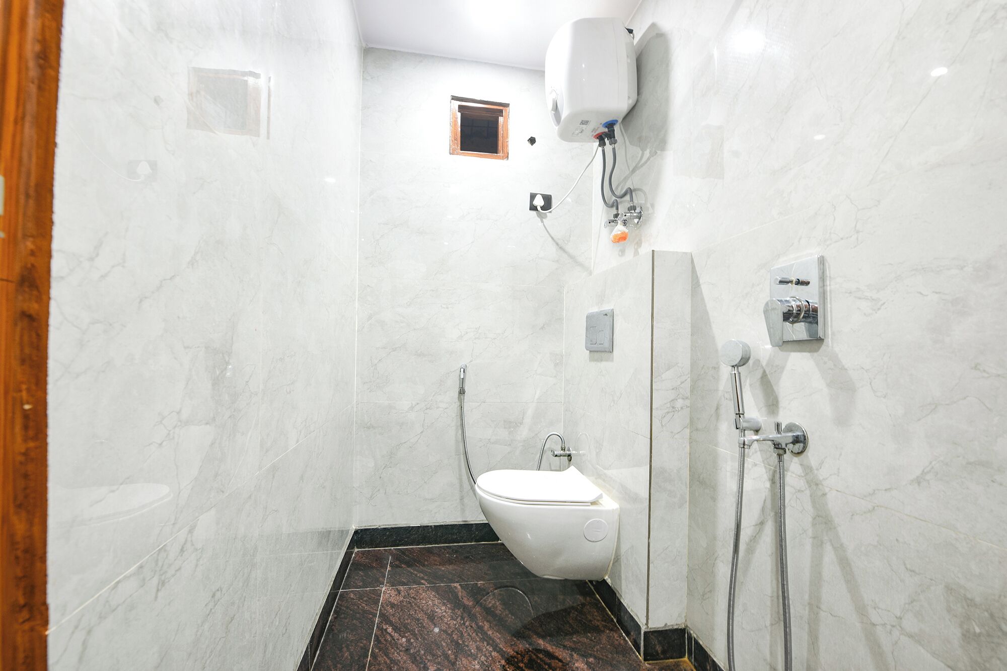 A bathroom with a toilet, a shower, and a water heater mounted on the wall.