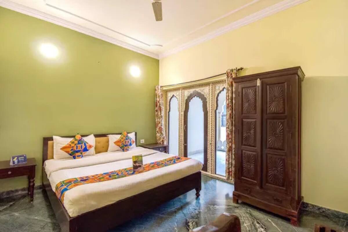 Un dormitorio con cama, armario y ventana con cortinas.