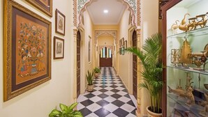 Un pasillo con piso a cuadros, obras de arte enmarcadas en las paredes y plantas en macetas.