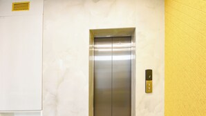 A modern elevator with a metallic finish, a control panel on the right, and a plain wall with a yellow accent. - FabHotel The White Cliff Inn - Near Max Hospital Saket (New Delhi)