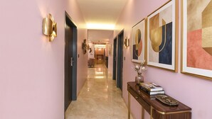 A hallway with a marble floor, framed artwork on the walls, and a console table with books and decorative items. - FabHotel The White Cliff Inn - Near Max Hospital Saket (New Delhi)