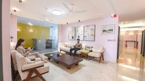 A modern hotel lobby with seating areas, a coffee table, ceiling fans, and artwork on the walls. - FabHotel The White Cliff Inn - Near Max Hospital Saket (New Delhi)