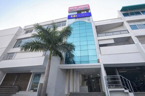 Un hôtel moderne, reconnaissable à son enseigne bien visible indiquant « Hotel Grand » et « Fab Hotels ».