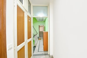 Un pasillo estrecho con puertas de madera y una pared verde.