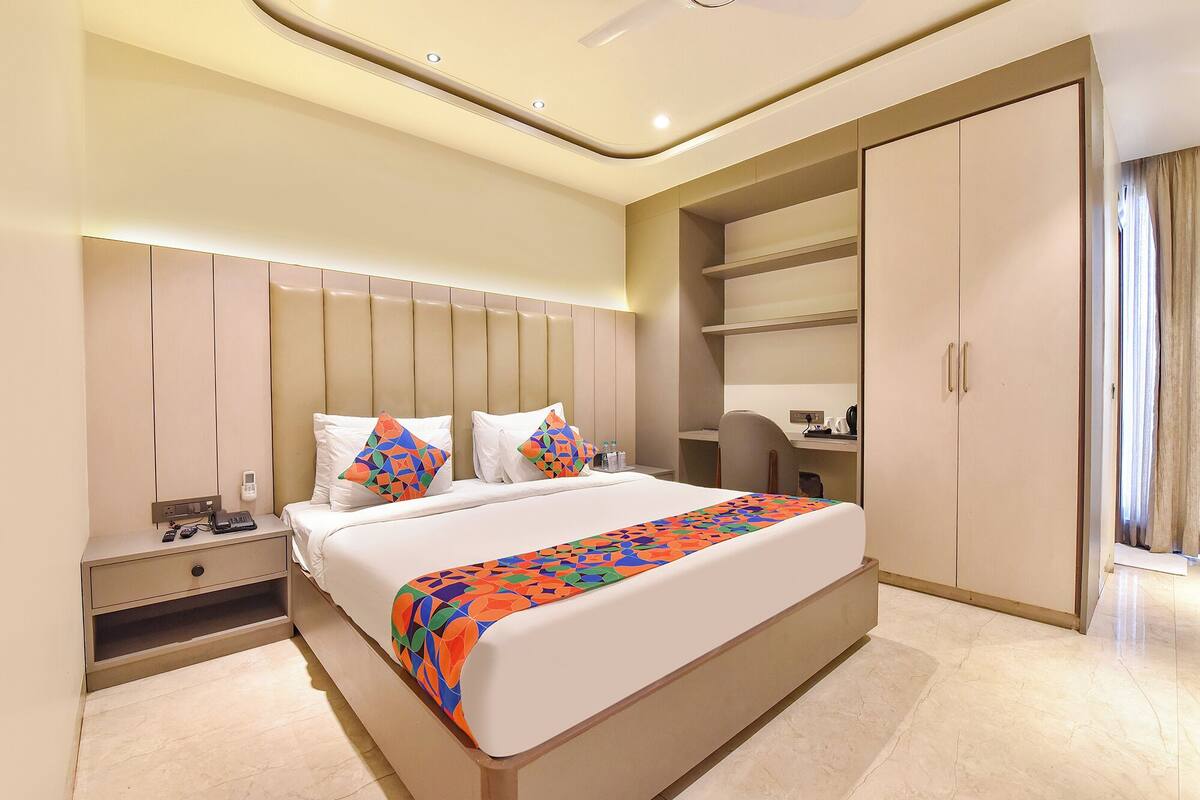 Ein Hotelzimmer mit einem großen Bett, einem Schreibtisch, einem Kleiderschrank und einem Telefon auf dem Nachttisch.