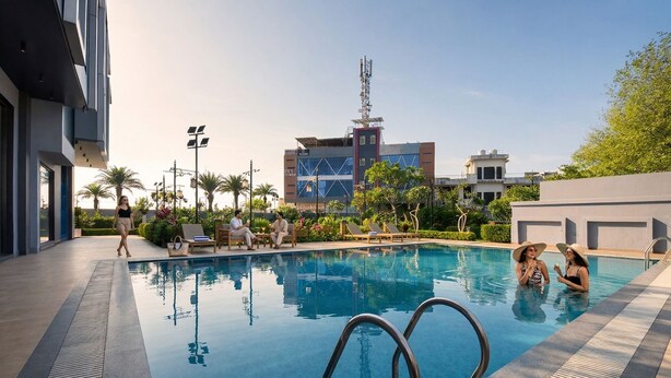 A swimming pool with lounge chairs, a building with a blue facade, and palm trees. - Fabhotel Elite Park Inn (Jaipur)