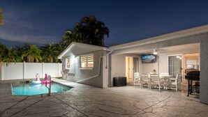 Una casa amb piscina, mobiliari exterior i un piano.