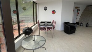 A modern interior with a dining area, a glass table, and a view through large windows. - Finca La Cruz (El Penol)