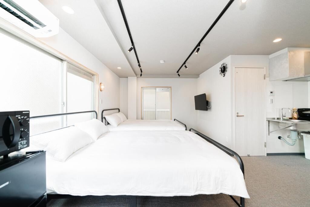 Ein Hotelzimmer mit Bett, Nachttisch, Klimaanlage und einem an der Wand montierten Fernseher.
