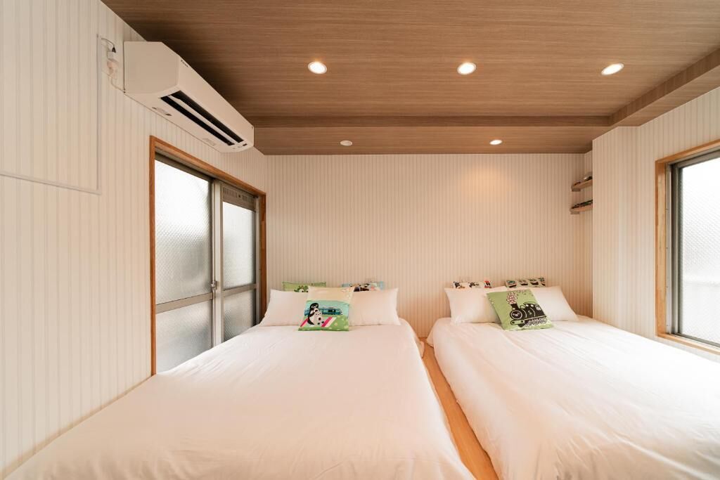 A room with two beds, a wooden ceiling, and a window.