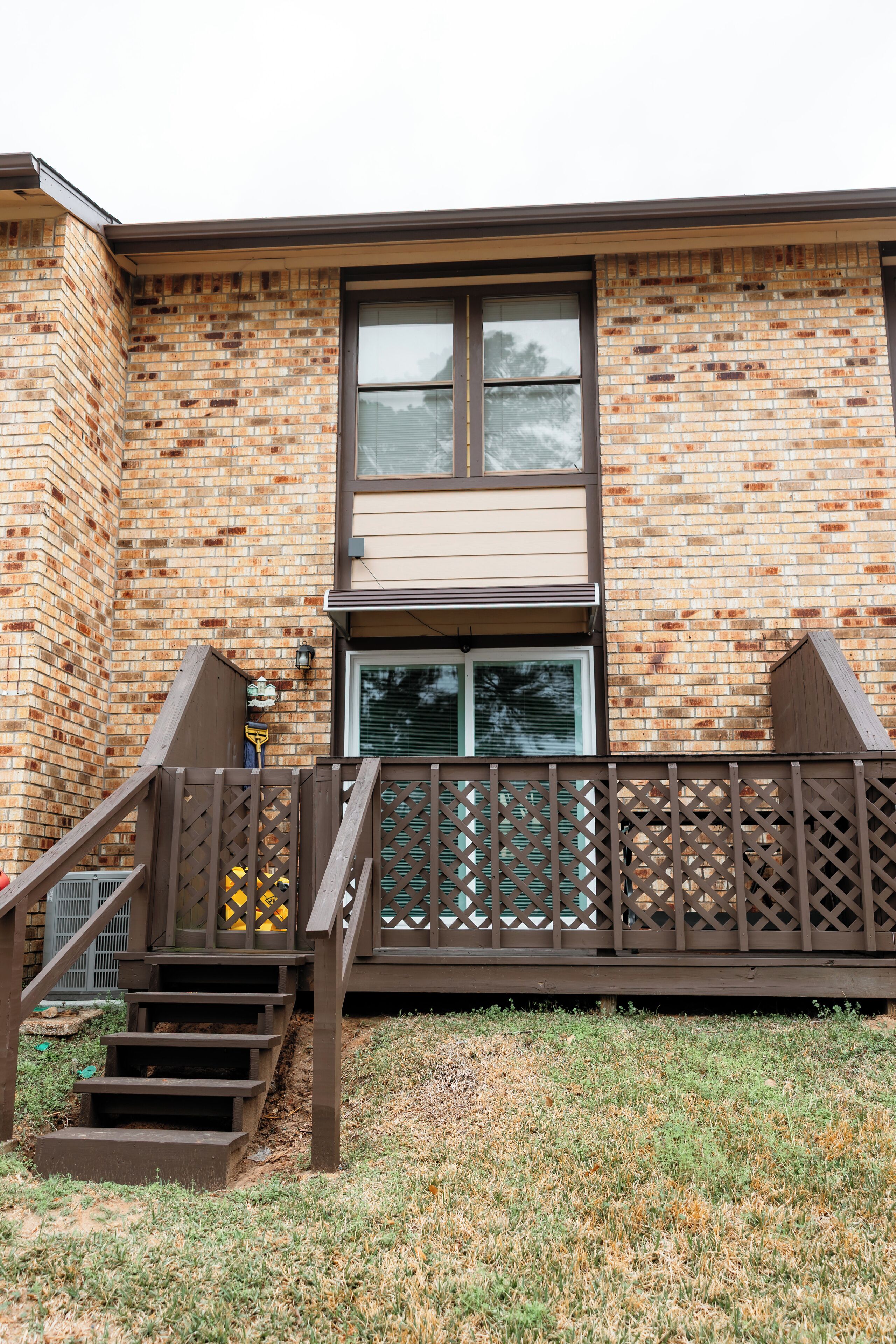 A brick building with a window, a wooden staircase, and a fence.