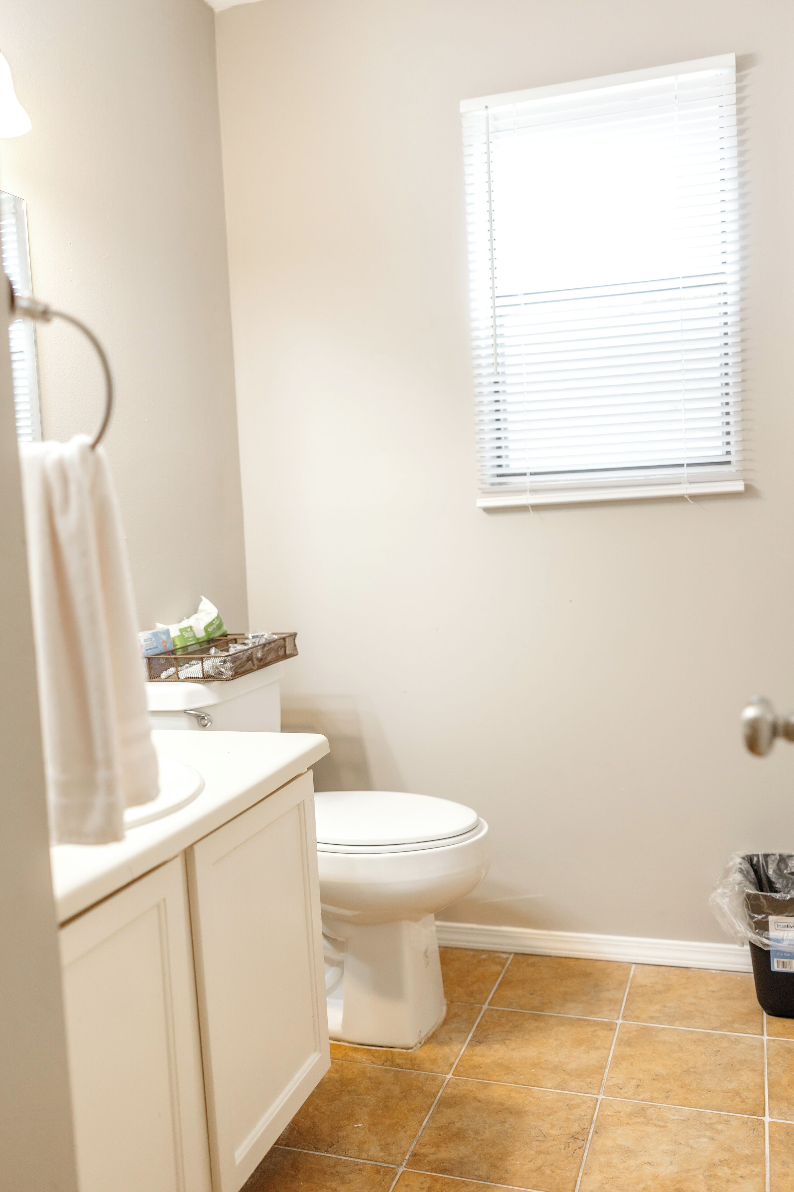 A bathroom with a toilet, white sink, and cabinet.