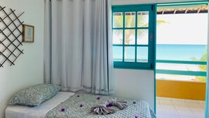 Un dormitorio con cama, ventana con vista al mar y puerta que da a un espacio exterior.