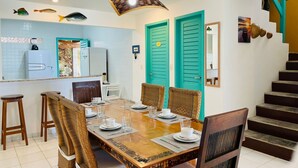 Un comedor con una mesa de madera dispuesta para cuatro personas, rodeado de sillas de mimbre.