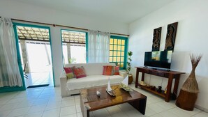 Una sala de estar con sofá, mesa de centro, televisor y elementos decorativos.