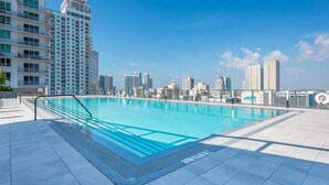 Piscina no terraço com paisagem urbana ao fundo.