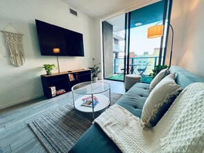 A modern living room with a flat-screen TV, a glass coffee table, a sofa, and a view of the city through large windows. - World Cup Escape•Pool•Gym•Downtown•Balcony•Modern (Miami)