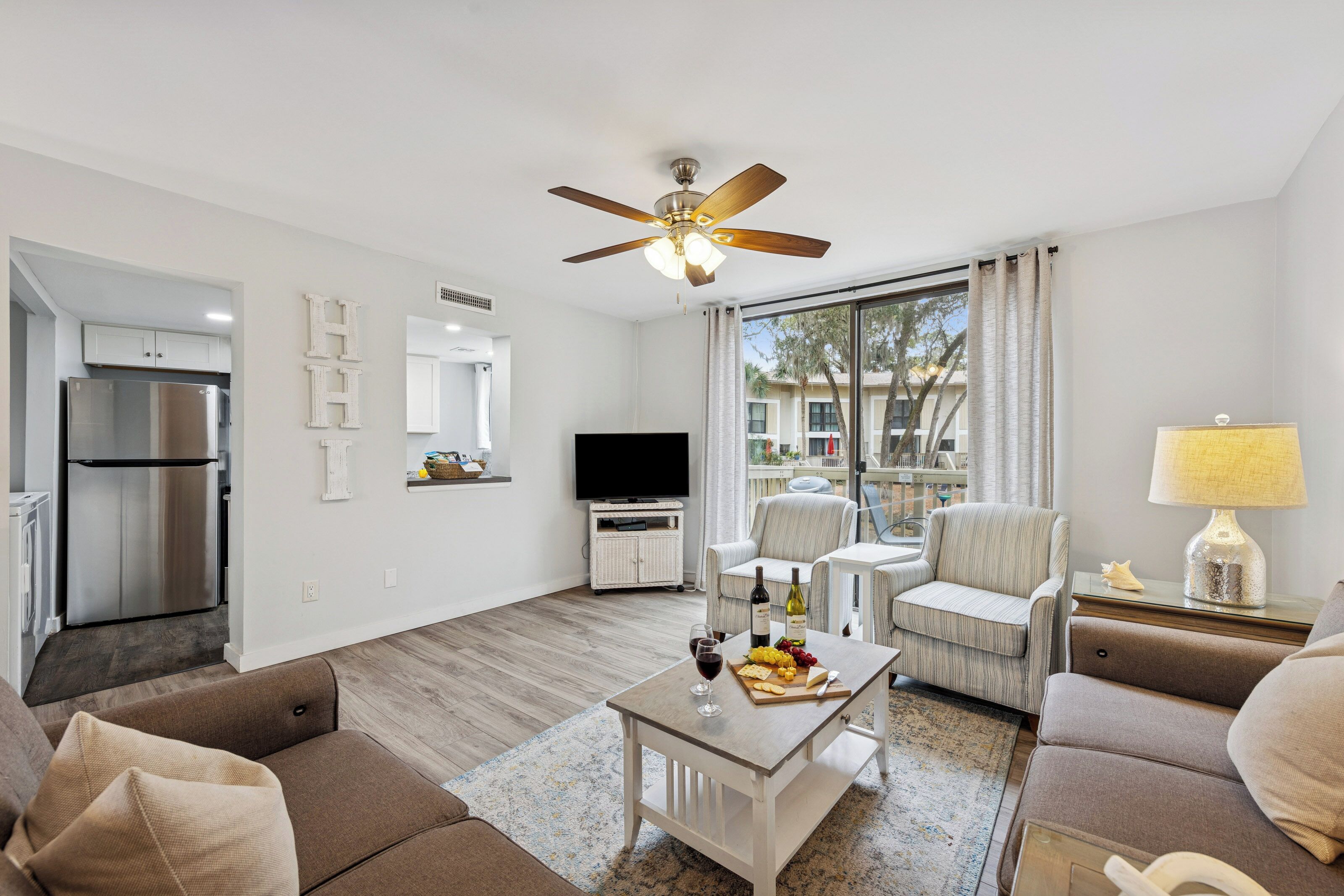 Een moderne woonkamer met een flatscreen televisie, een plafondventilator en een eethoek met een tafel gedekt voor een maaltijd.