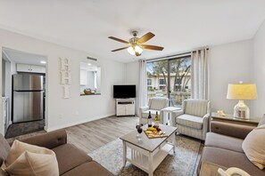 A modern living room with a flat-screen TV, a ceiling fan, and a dining area with a table set for a meal. - 2BR Seascape Villa, 0.2 Mi to Private Beach Amenities, Walk to Dining & Shops (Hilton Head Island)