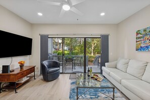 A living room with a flat-screen TV, a sofa, a coffee table, and a dining area with chairs and a table. - 8 Ocean Breeze @ Forest Beach | Pet-Friendly | Community Pool & Tennis | Modern Interiors (Hilton Head Island)