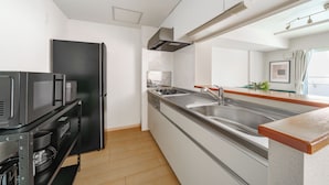 A modern kitchen with a built-in oven, a stainless steel sink, and a black refrigerator. - E-US NAEBO STATION 103 (Sapporo)