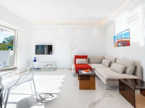 Ein modernes Wohnzimmer mit einer Couch, einem Couchtisch und einem an der Wand befestigten Fernseher.