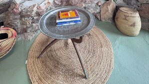 Un'accogliente area con divanetti, una parete in pietra, una panca imbottita con cuscini decorati, un cesto di vimini e un libro intitolato "The Horse" su un vassoio di metallo.
