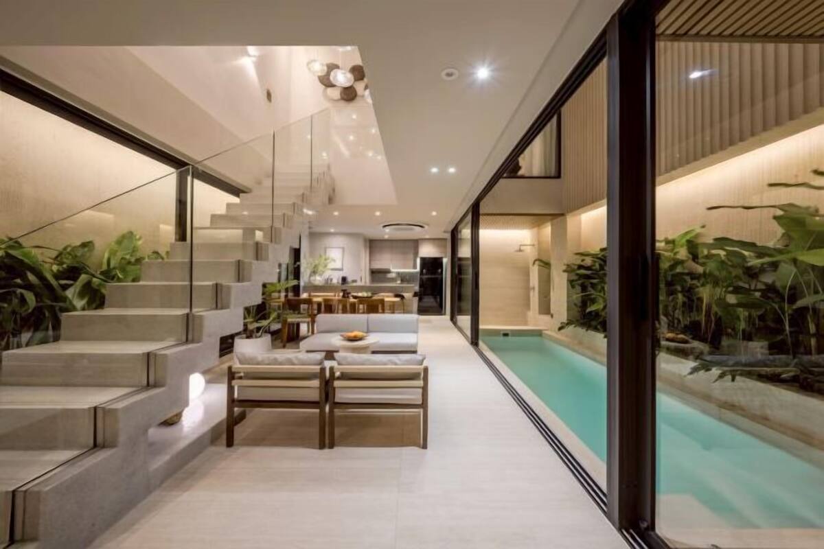 A modern interior with a staircase, a dining area, and a pool.