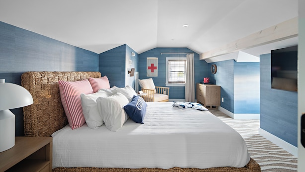 A bedroom with a large bed, a bedside table, a chair, a small desk, and a window with curtains. - New Crow’s Nest Ocean View l Downtown l Queen Suite (Newburyport)