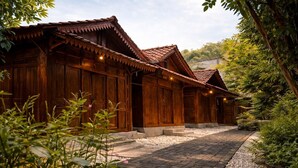 A traditional wooden building with a tiled roof, surrounded by greenery and a cobblestone pathway. - Dapur Alit Villas (Kasihan)