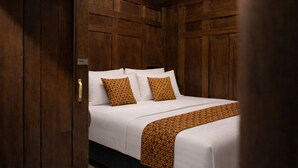 A wooden-paneled room with a bed, two pillows, and a patterned throw blanket. - Dapur Alit Villas (Kasihan)