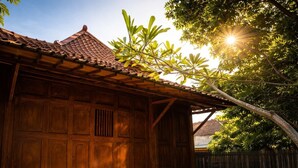 A traditional wooden house with a tiled roof, large wooden doors, and a covered porch area. - Dapur Alit Villas (Kasihan)