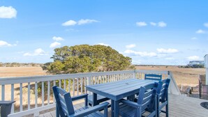 A wooden deck with a table and chairs, overlooking a field and a tree. - "Once in a Blue Moon - 796 OBW" 4 Bedroom, Second Row (Supply)