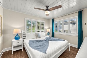 A bedroom with a bed, nightstands, a ceiling fan, and windows with shutters. - Holiday House | Steps to Siesta Beach, Pet Friendly, Walk to Village (Siesta Key)