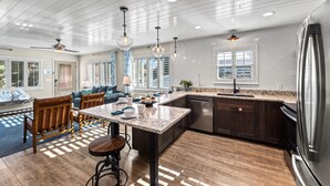 A modern kitchen with a central island, dark wood cabinets, stainless steel appliances, and pendant lighting.