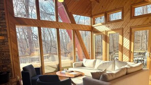 Ein gemütliches Wohnzimmer mit großem Fenster, einer Couch, einem Couchtisch und einem Kamin.