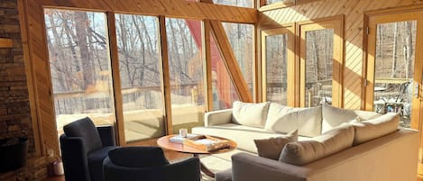 A cozy living room with a large window, a sofa, a coffee table, and a fireplace.