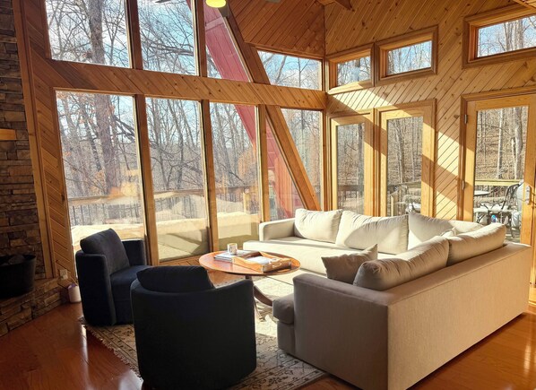 A cozy living room with a large window, a sofa, a coffee table, and a fireplace.