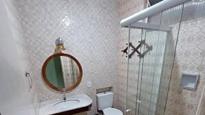 Une salle de bain équipée de toilettes, d’un lavabo et d’une douche à parois en verre.