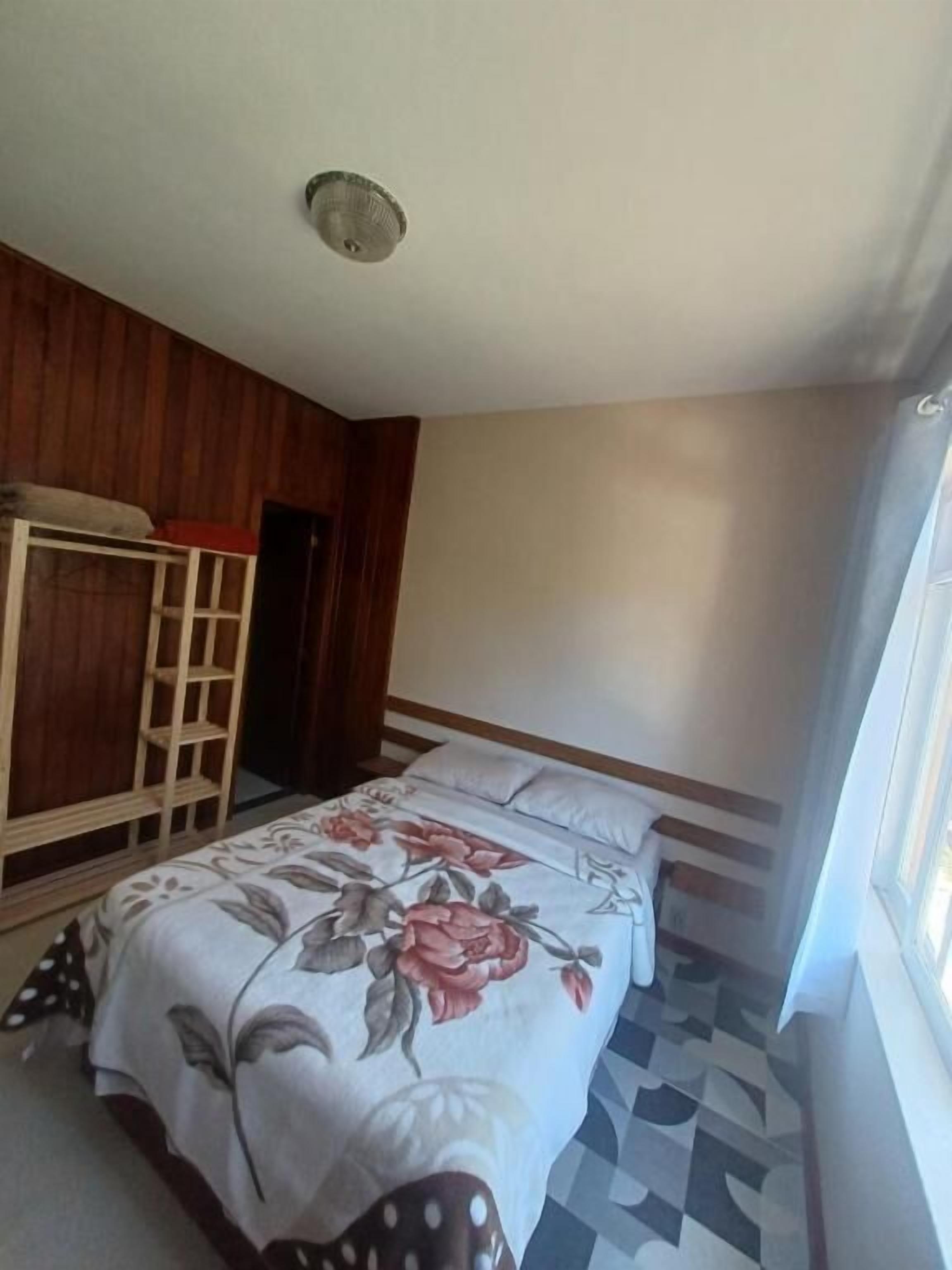 A bedroom with a bed, wooden bunk bed, and a window.