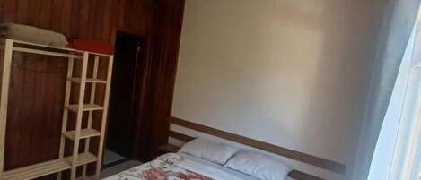 A bedroom with a bed, wooden bunk bed, and a window.